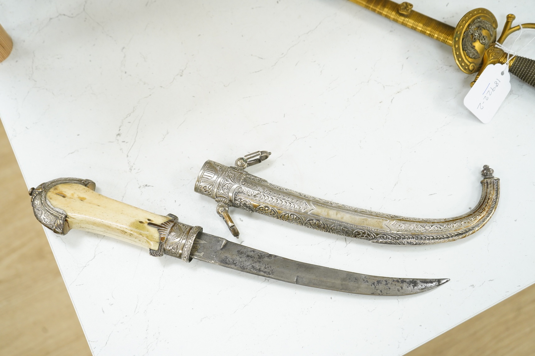 A silver mounted Moroccan dagger jambya, with silver sheath and hilt, mounts chased with foliate and floral designs, and one piece bone grip, blade as found, overall length 42cm
